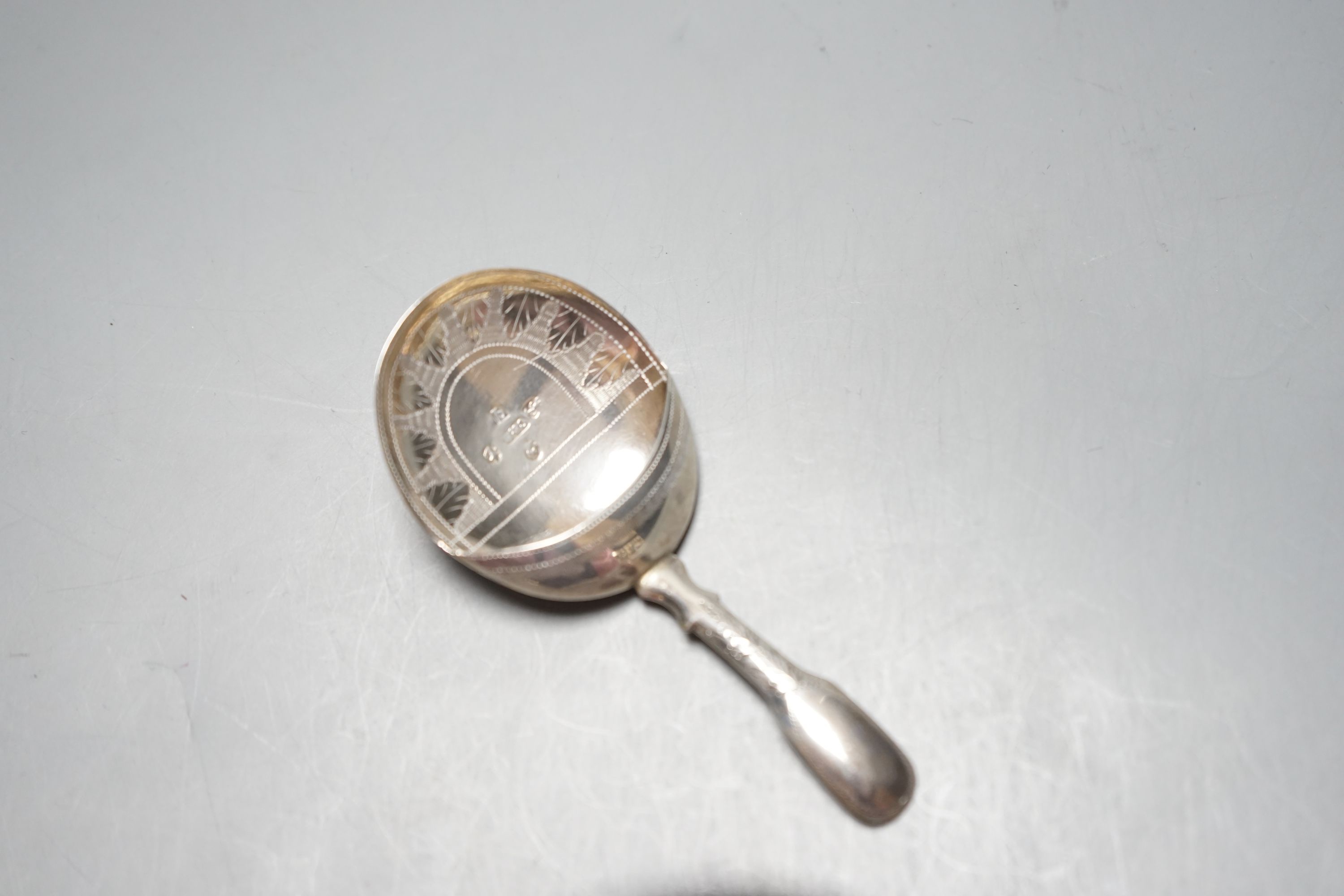 An Edwardian planished silver circular tobacco box, by George Unite, Birmingham, 1902, 79mm, a similar silver trinket box, a George III silver caddy spoons, Birmingham, 1814 and a modern silver teas strainer on stand.